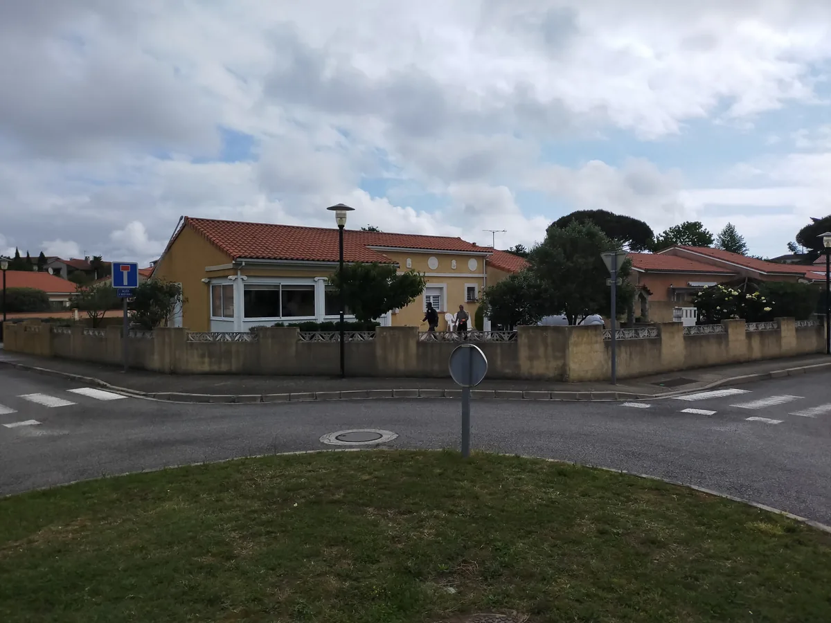 Avant : long mur de clôture à l'enduit terne et grisé