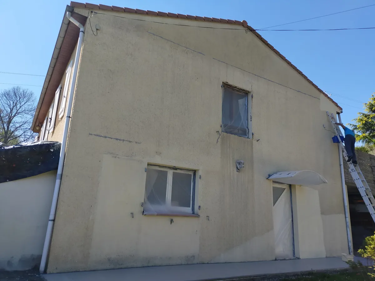 Avant : façade défraîchie, fenêtres bâchées, peintre sur l'échelle