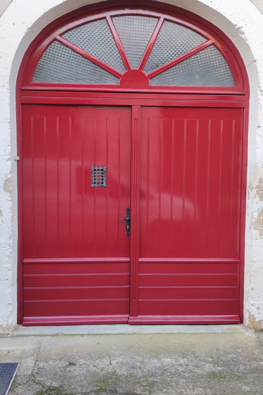 Après : porte de garage cintrée repeinte en rouge vif et uniforme
