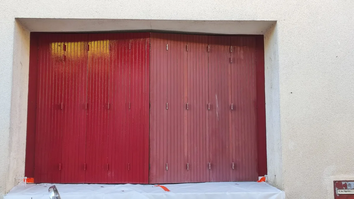 Porte de garage en cours de peinture : bâche au sol, adhésif de masquage sur le dormant et la façade protégée